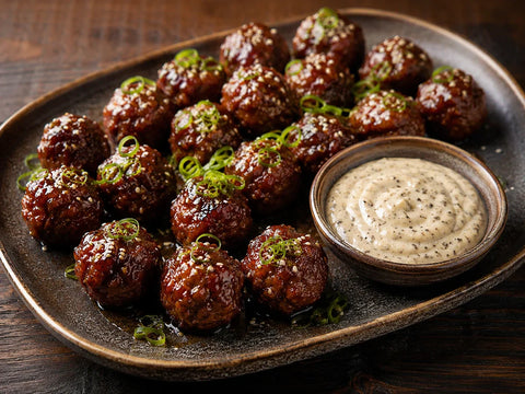Korean-inspired BBQ meatballs with sesame and sliced green onion arranged on a platter with creamy truffle mayonnaise dip.
