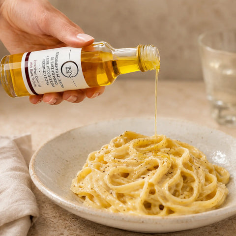 Olivenöl mit schwarzem Trüffelaroma wird über warme cremige Tagliatelle geträufelt