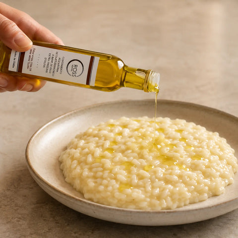 Olivenöl mit weißem Trüffelaroma wird über warmes cremiges Risotto geträufelt